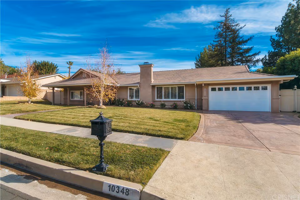 Front exterior of a single-story suburban house with a lawn, driveway, garage, and mailbox.