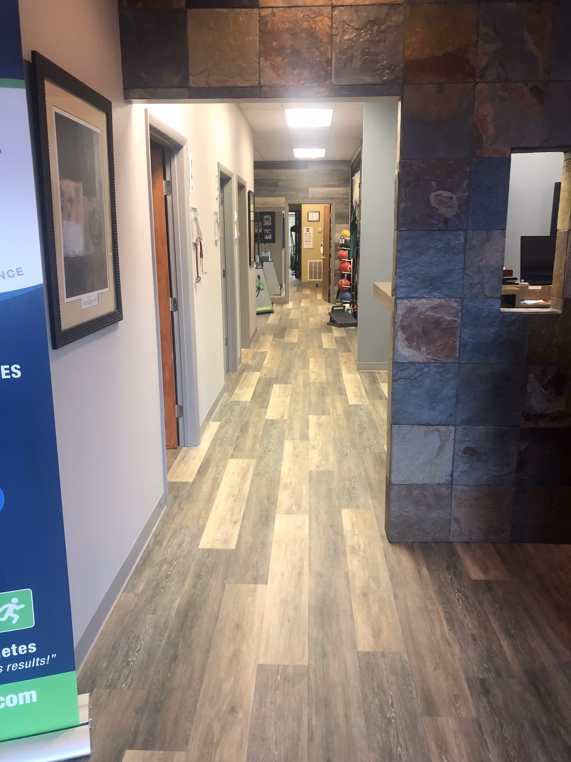 Interior hallway of a senior living facility with wood flooring and stone wall accents.