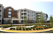 Exterior view of a multi-story senior living facility with a circular driveway and landscaping.