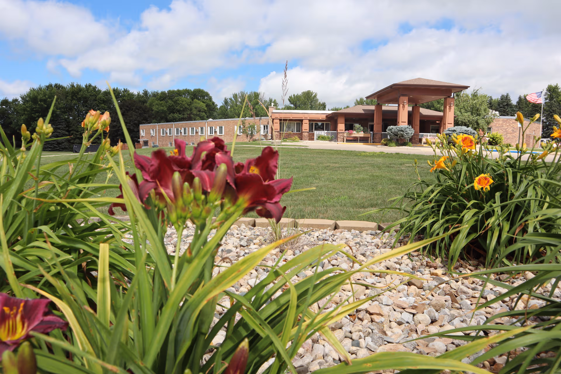 Exterior view of Osceola Senior Living with brick entrance and landscaped flower beds.