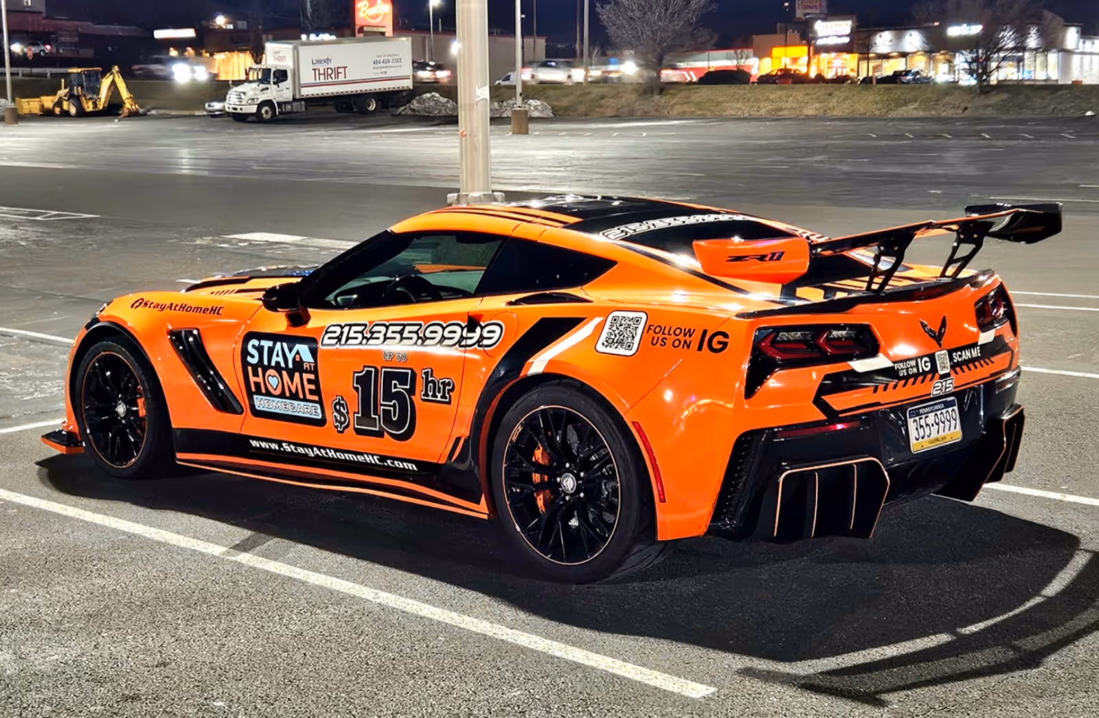 Orange branded sports car Stay at Home Homecare parked in a dimly lit lot.