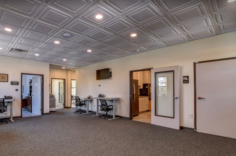 Interior common area with desks and doorway to a kitchenette.