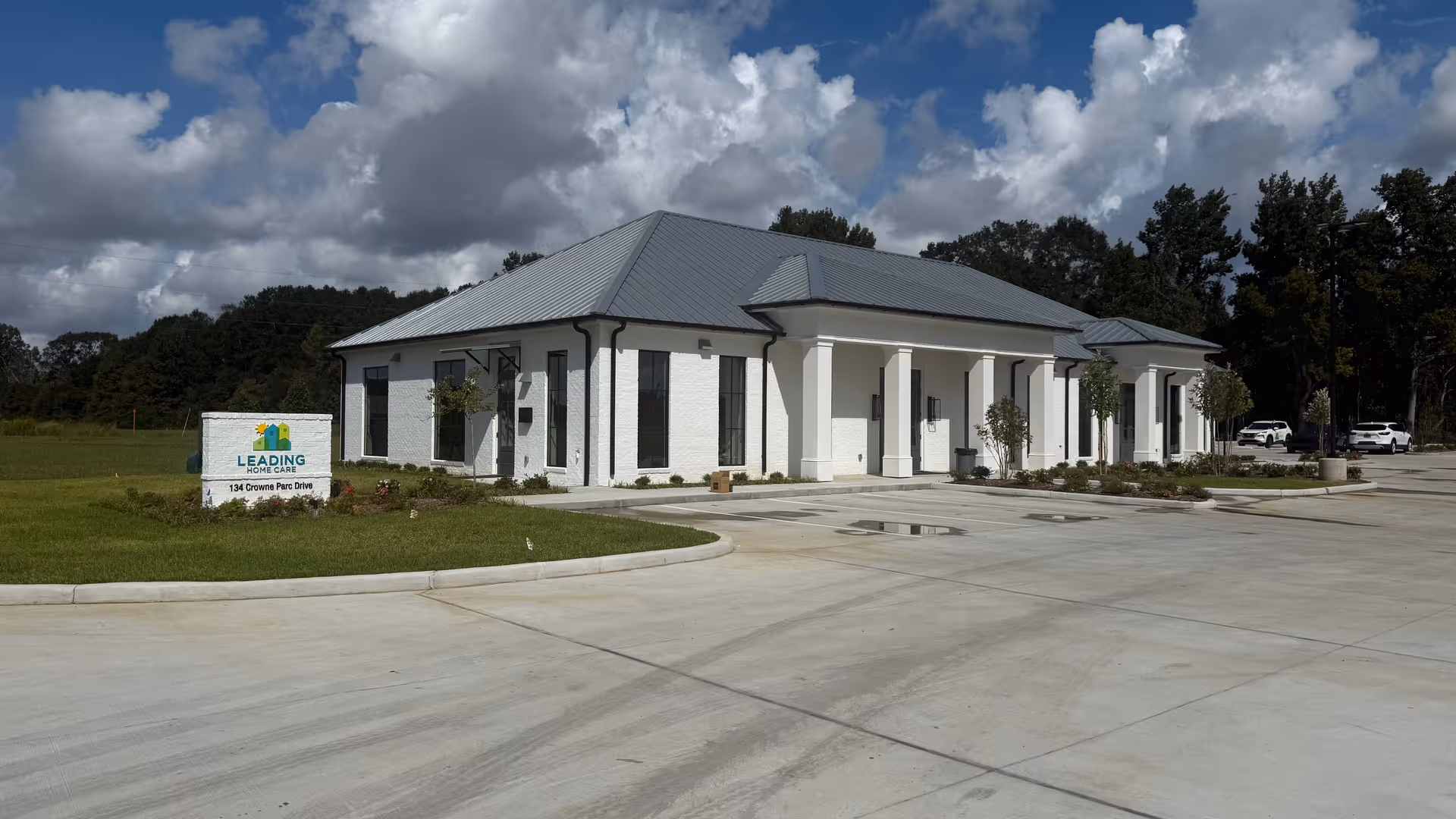 White, single-story care facility with a metal roof, columns, and a spacious front entrance.