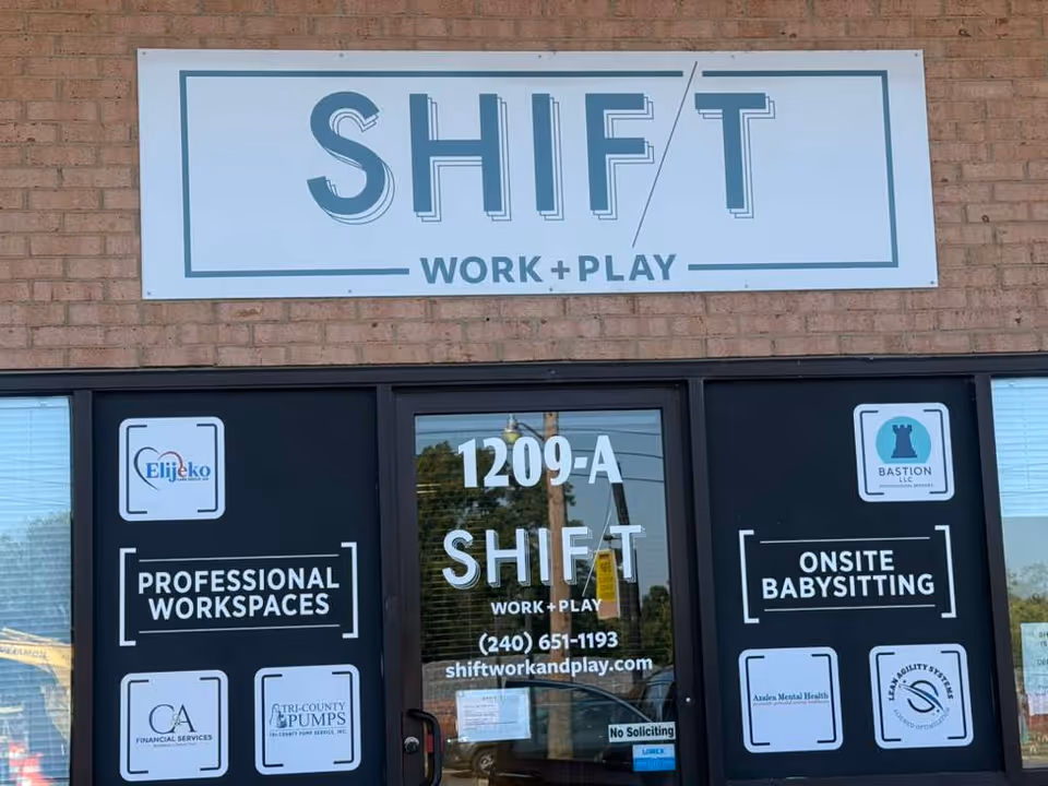 Brick storefront featuring SHIFT signage and windows advertising workspaces and babysitting.