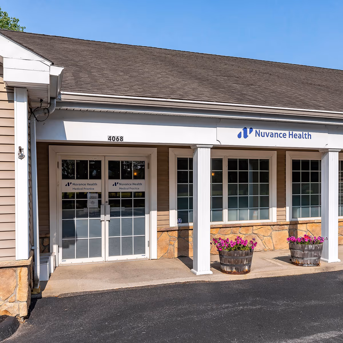 Front of a medical practice building with glass doors and flower planters.