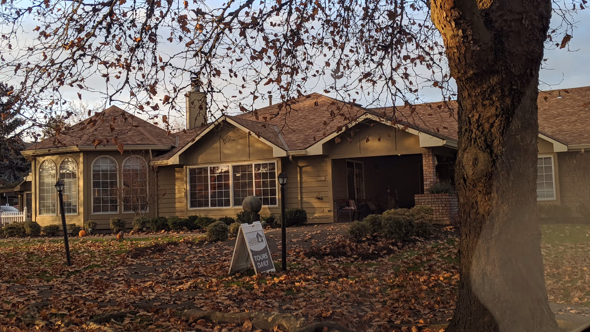 Conifer House senior living facility exterior with large windows and autumn leaves.