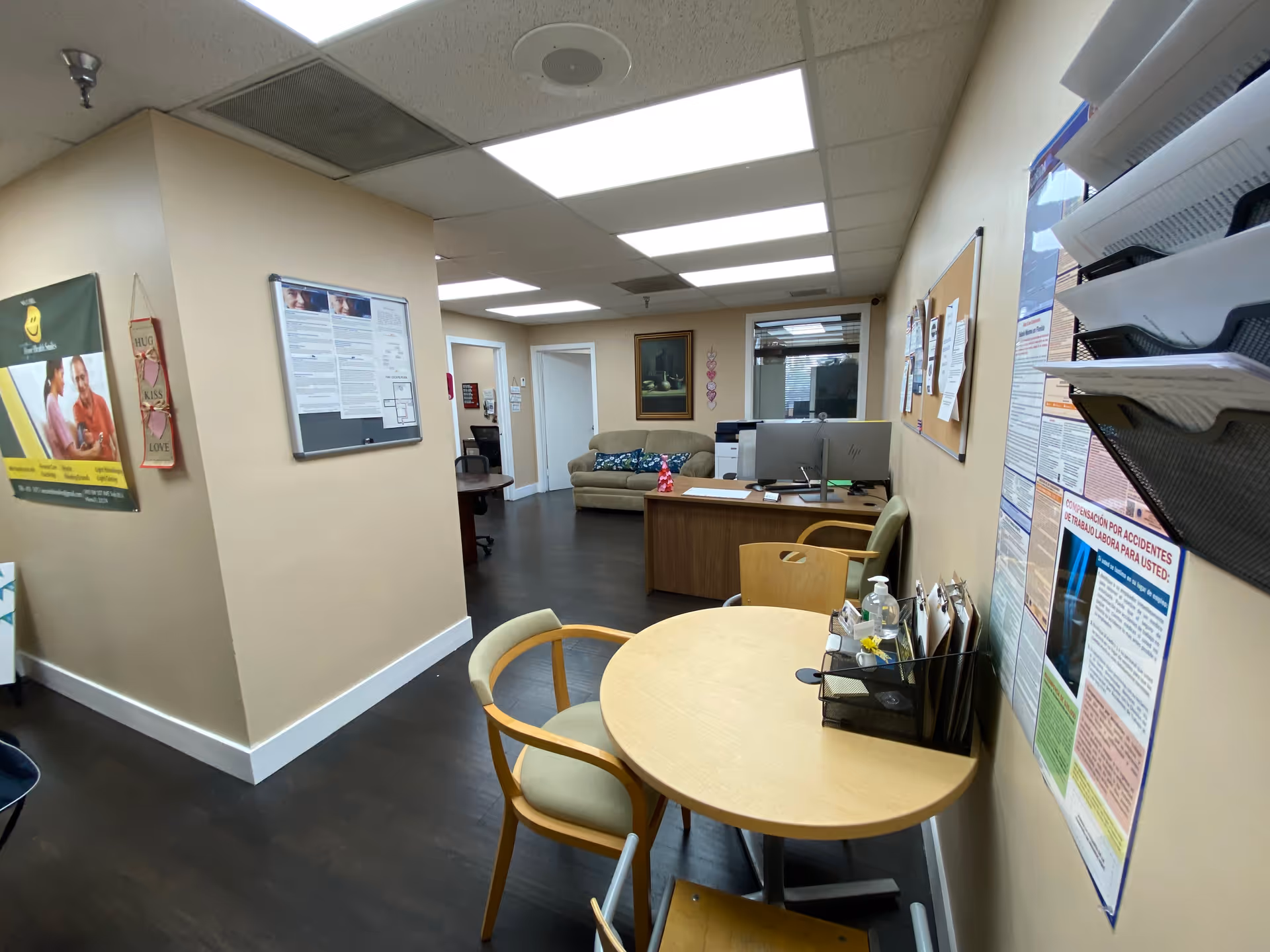 Interior of a senior facility reception area with table, chairs, bulletin boards, and computers.