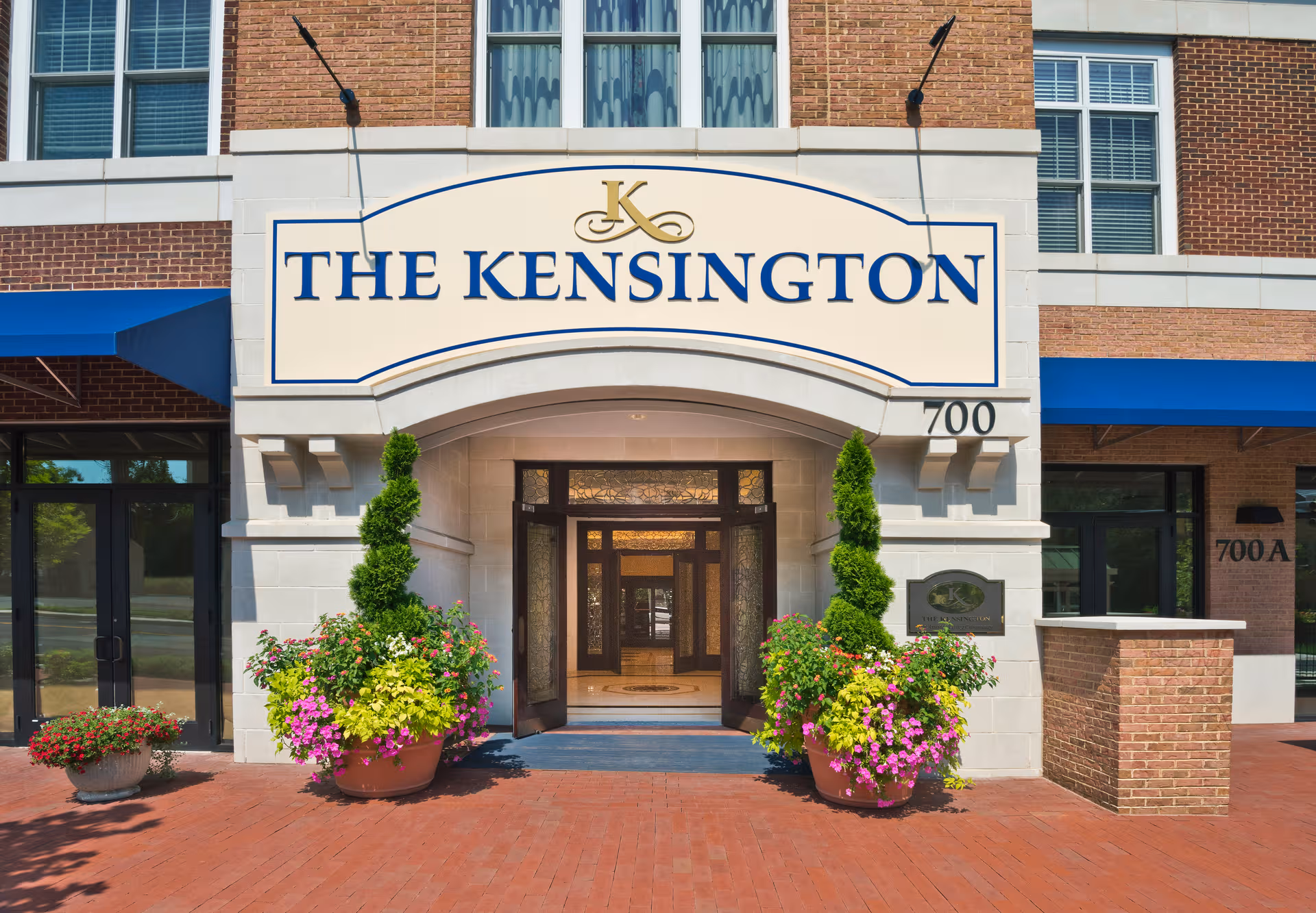 Front entrance of The Kensington Falls Church with large sign and decorative planters.