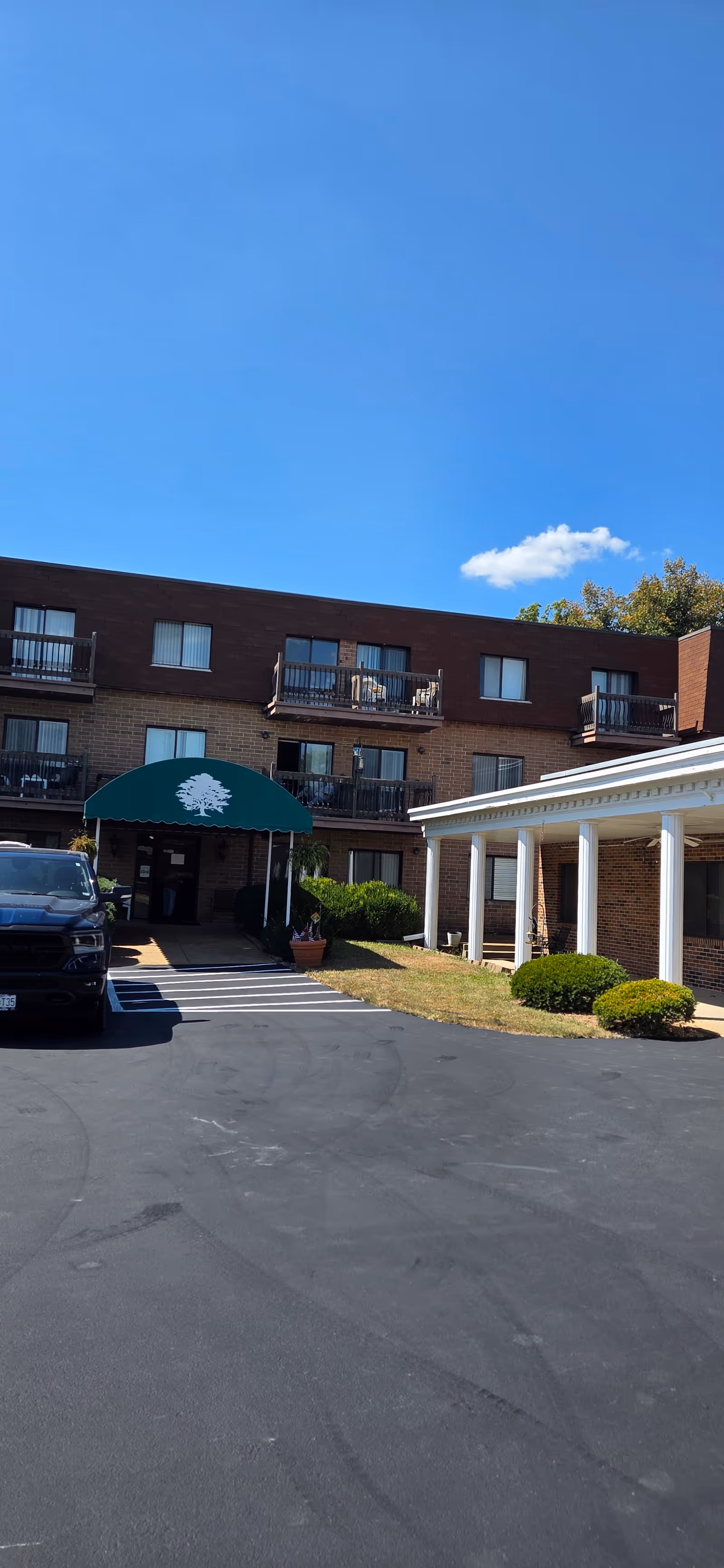 Exterior view of Marymount Manor: brick building, green awning, and surrounding parking area.