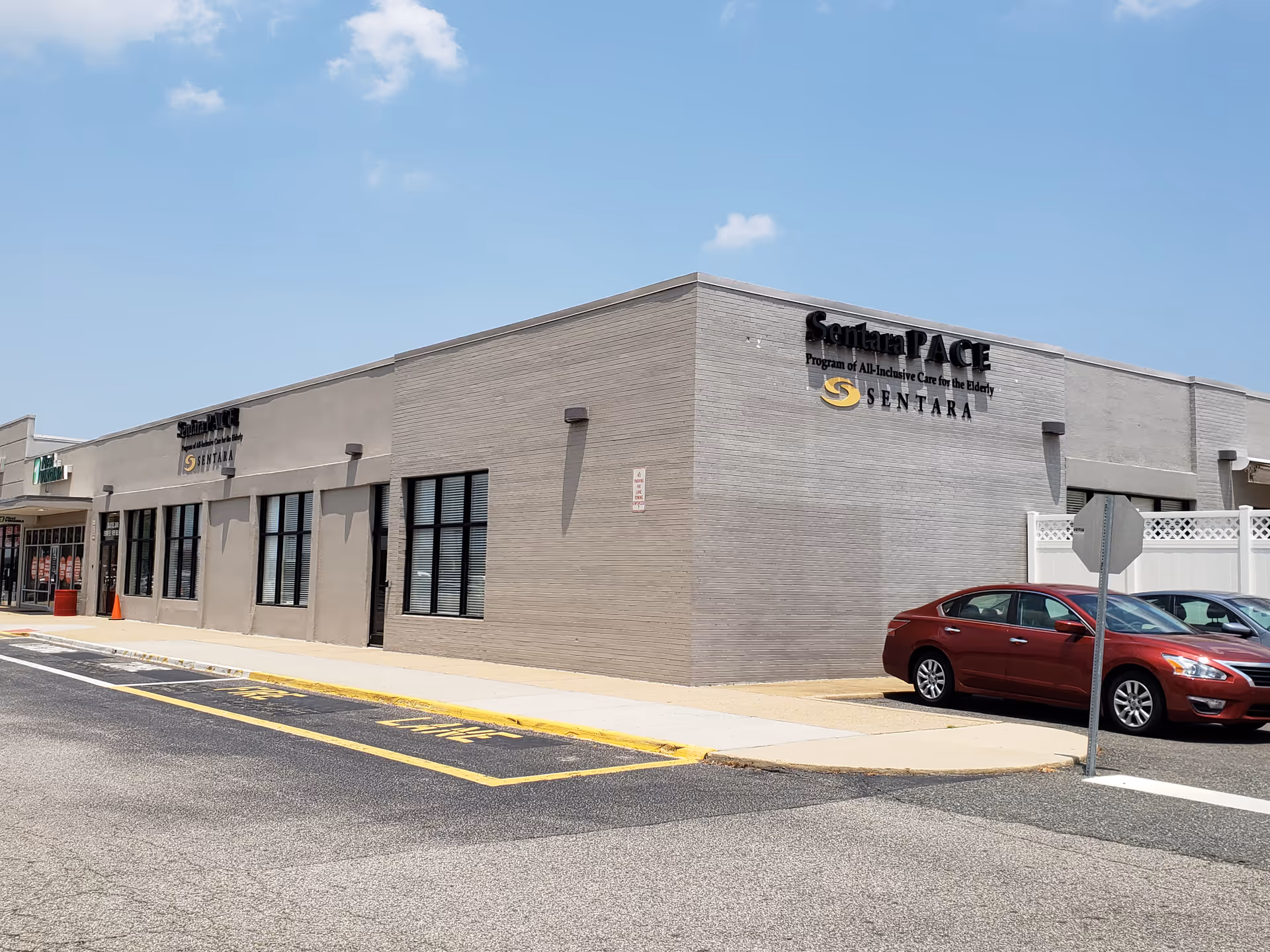 Exterior view of Sentara PACE building with parking lot and red sedan.