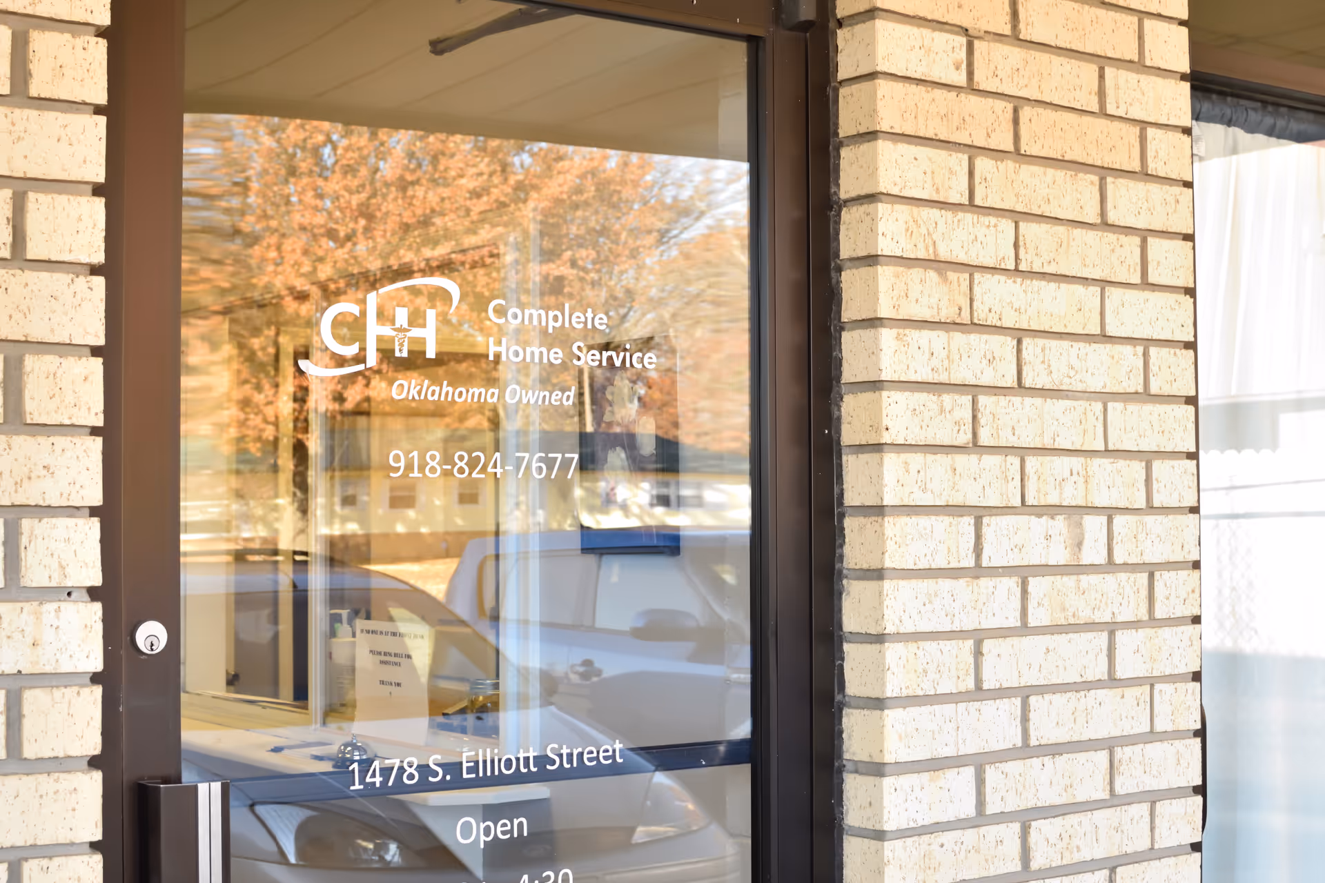 Glass door with Complete Home Service logo and brick building exterior