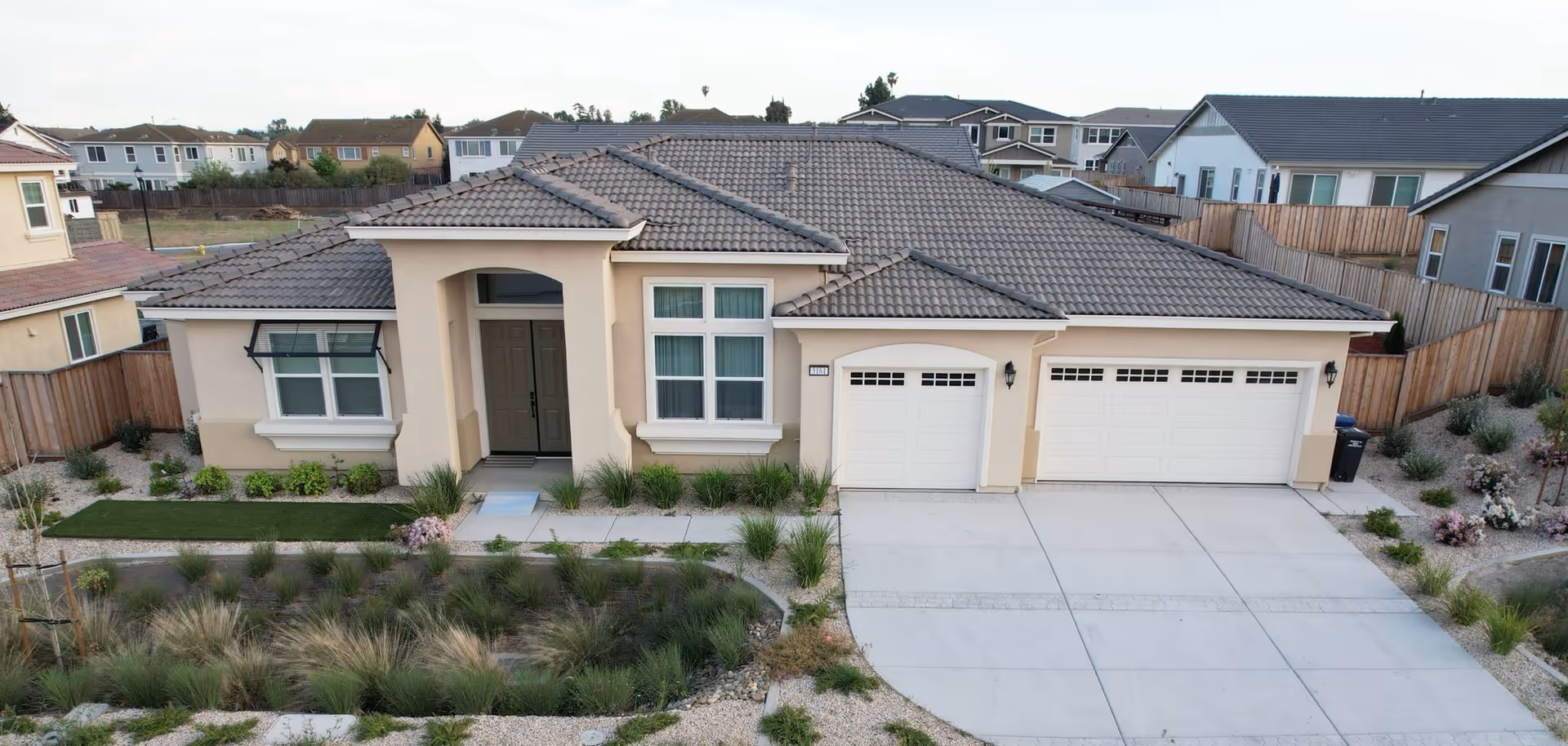Front exterior view of a single-story beige residence with a three-car garage.