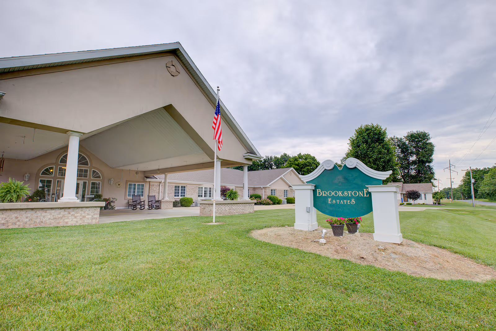 Front view of Brookstone Estates entrance with sign, flag, and covered driveway.