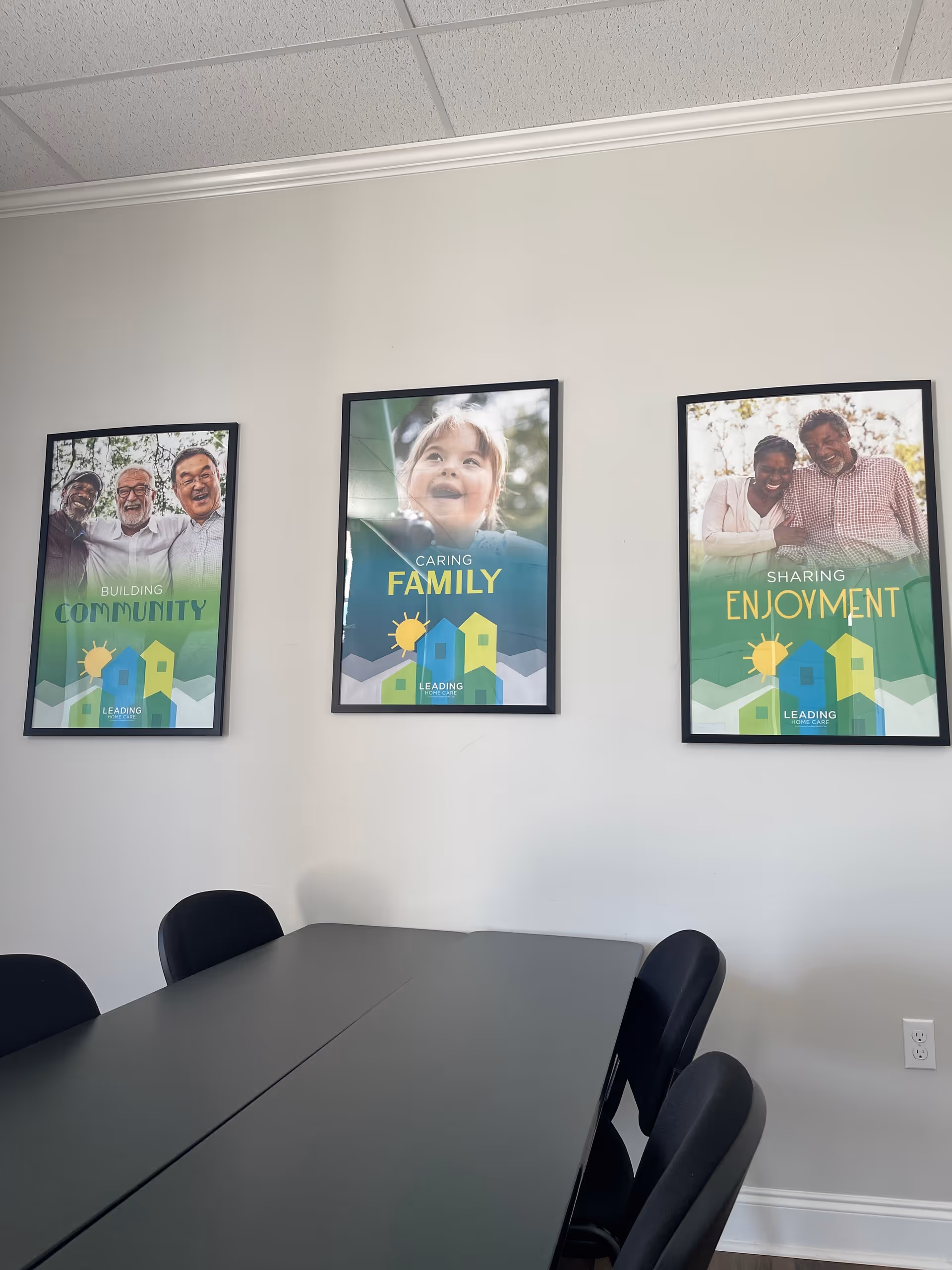 Conference room with a long table, black chairs, and framed posters on the wall.