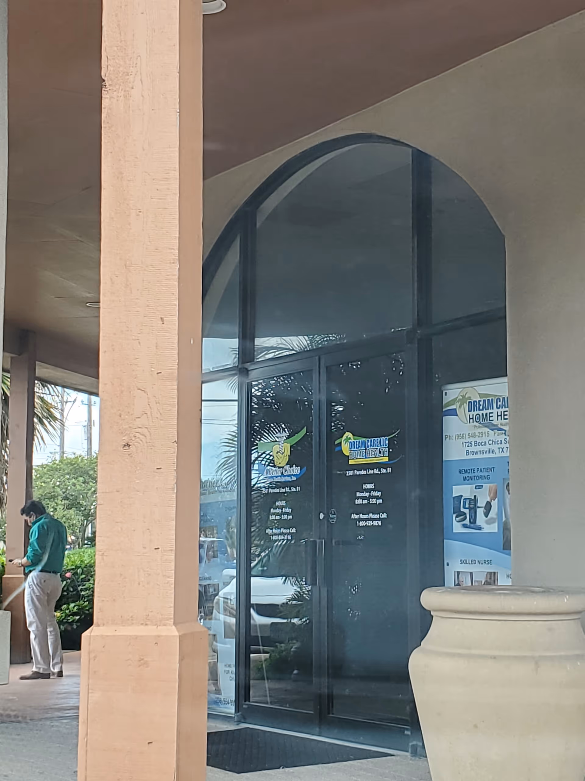 Exterior view of the facility entrance with glass doors and signage, plus a person standing nearby.