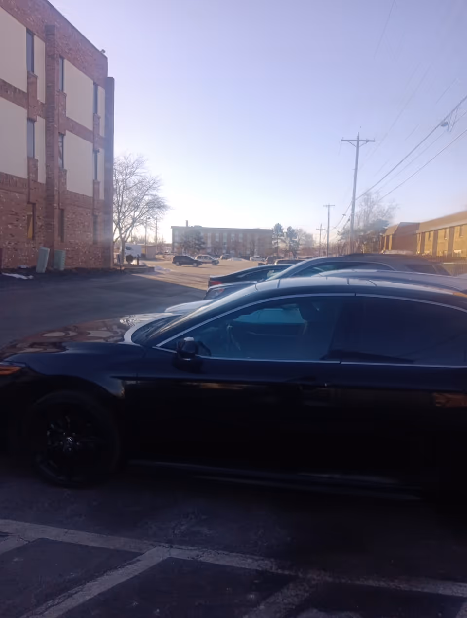 Exterior view of a brick senior living building with parked cars.
