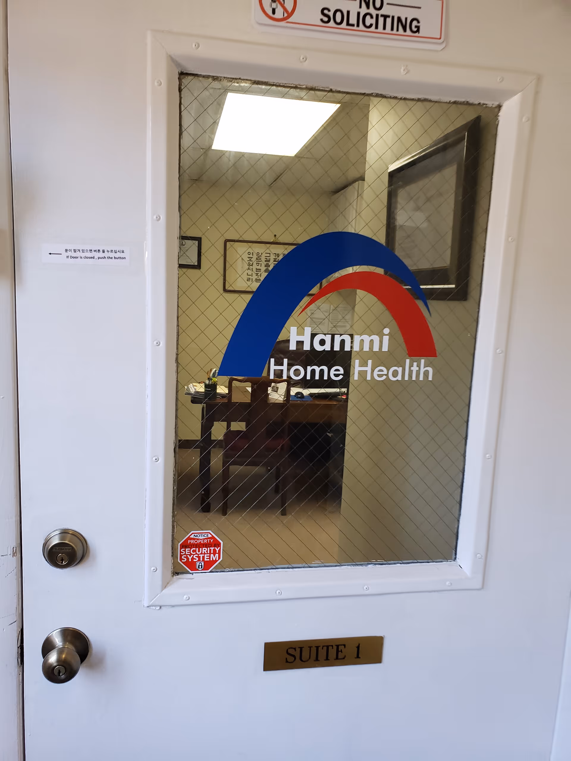 A white door with glass panel showing Hanmi Home Health logo and a small office inside.