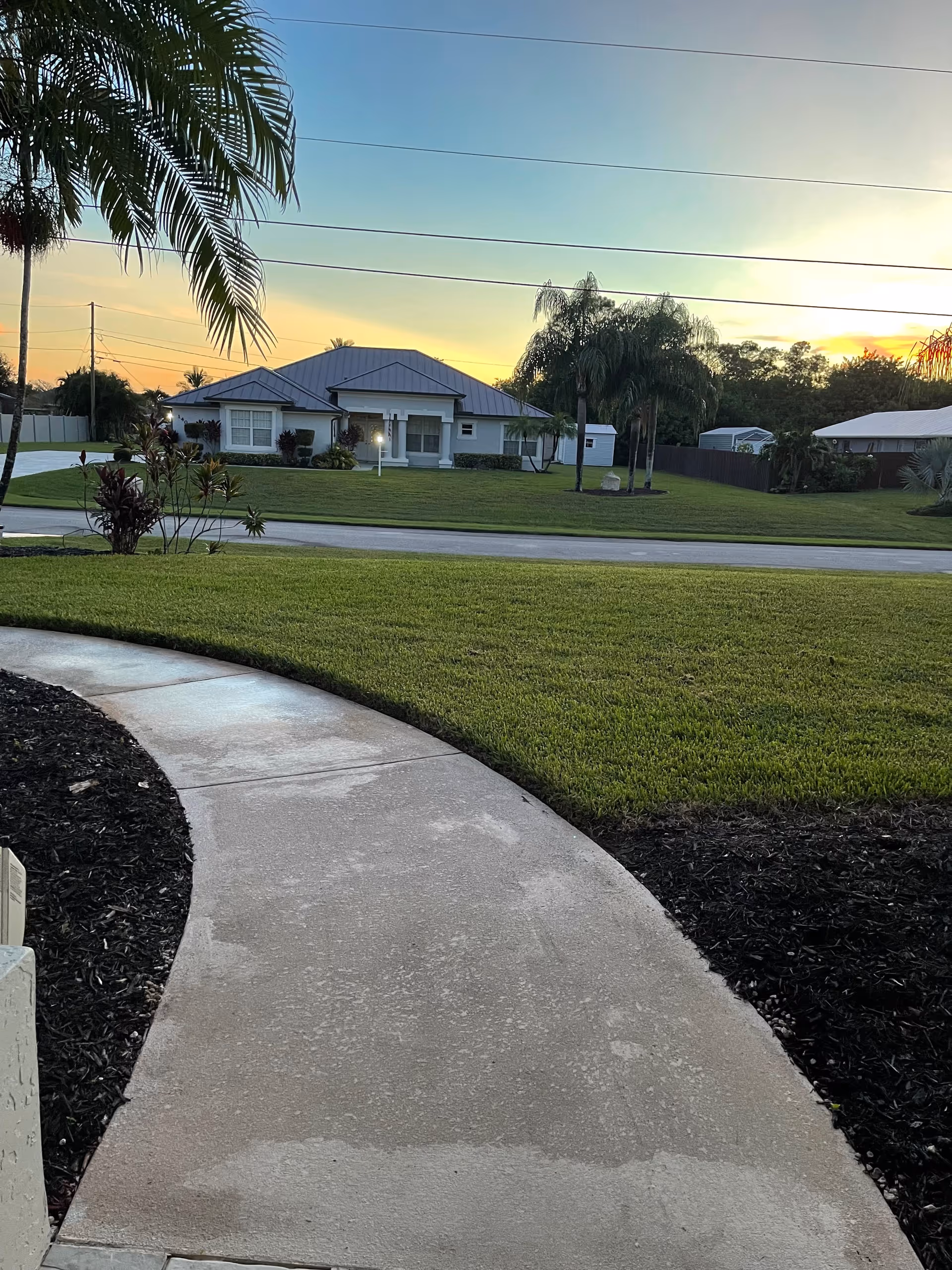 Exterior view of a single-story assisted living facility with a curved walkway and palm trees.