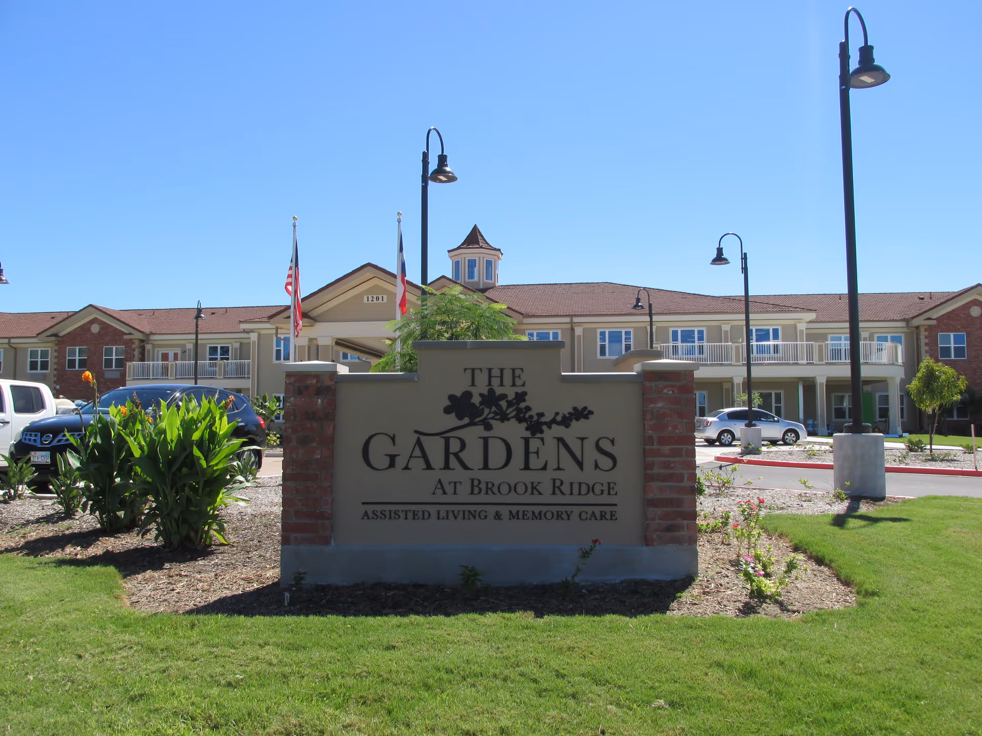 Exterior view of The Gardens at Brook Ridge facility with sign and cars