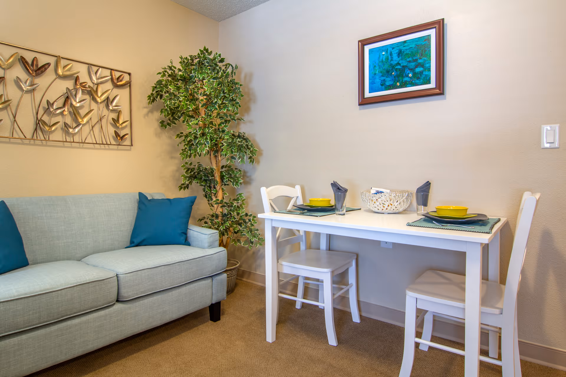 Cozy living area with pale blue sofa, plant, and dining table with chairs.