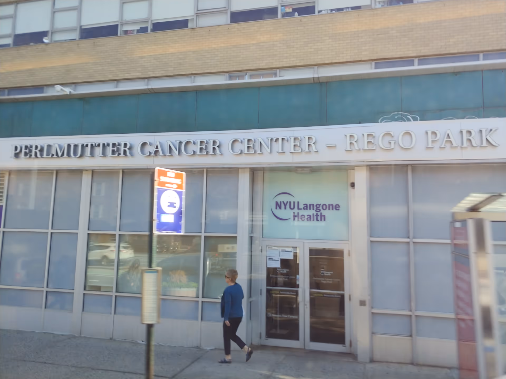 Exterior view of Perlmutter Cancer Center – Rego Park, NYU Langone Health, with a passerby.