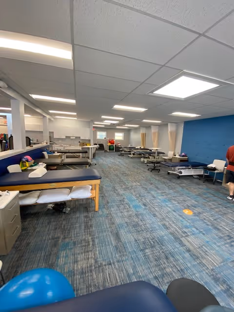Interior rehabilitation gym with multiple treatment tables and therapy equipment.