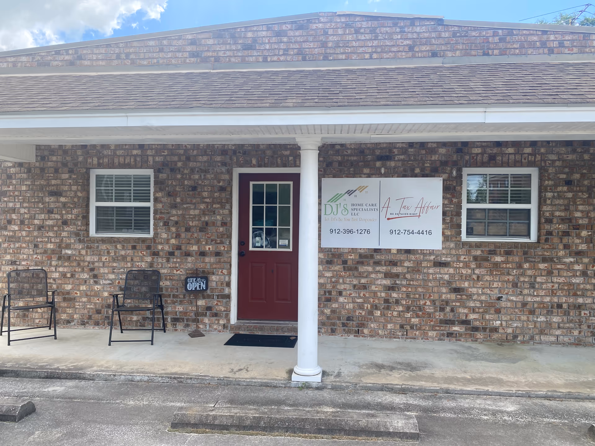 Brick exterior of a senior care facility with a red door, windows, chairs, and signage.