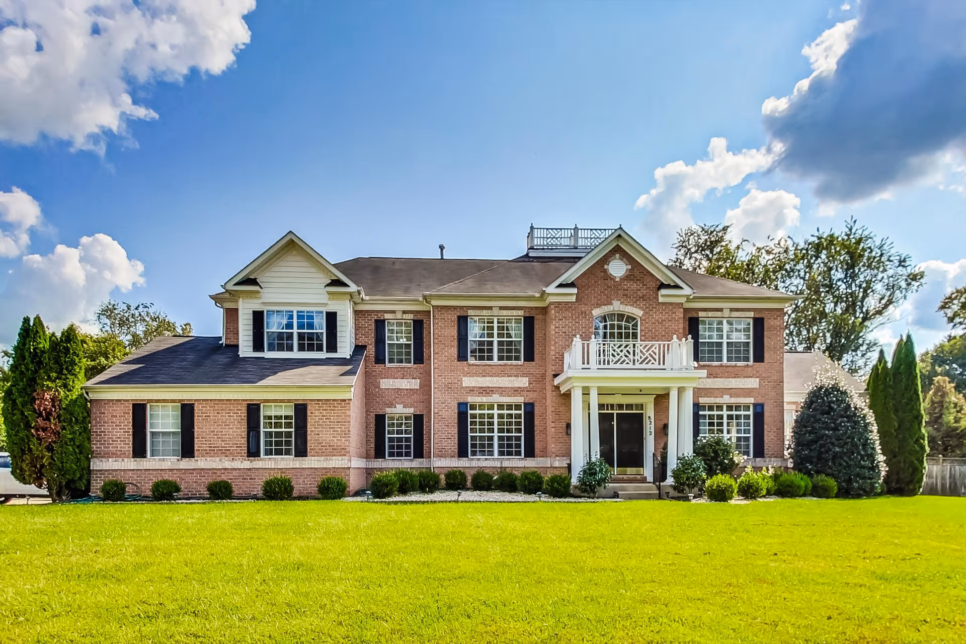 Brick two-story assisted living building with white columns and manicured front lawn.