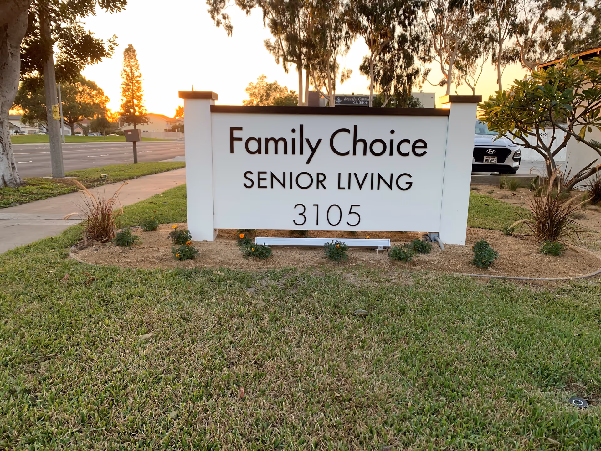 A white Family Choice Senior Living sign on a grassy front yard