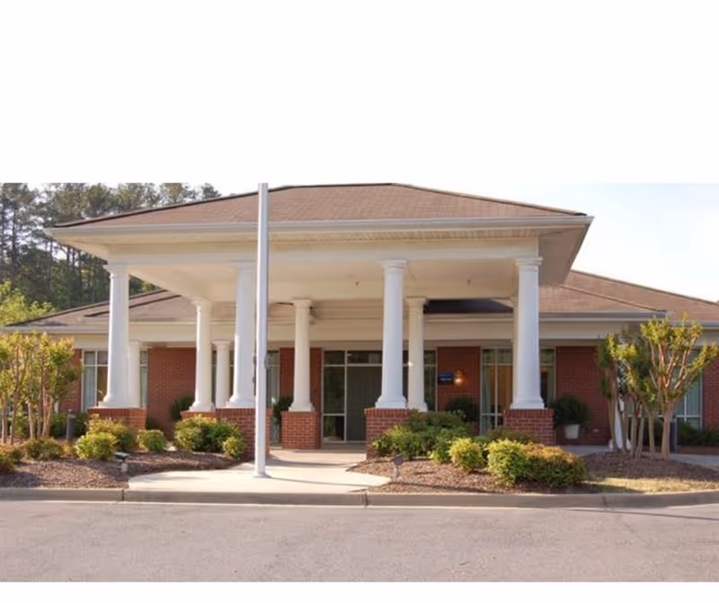Front view of a brick senior living facility with white columns and a covered entrance