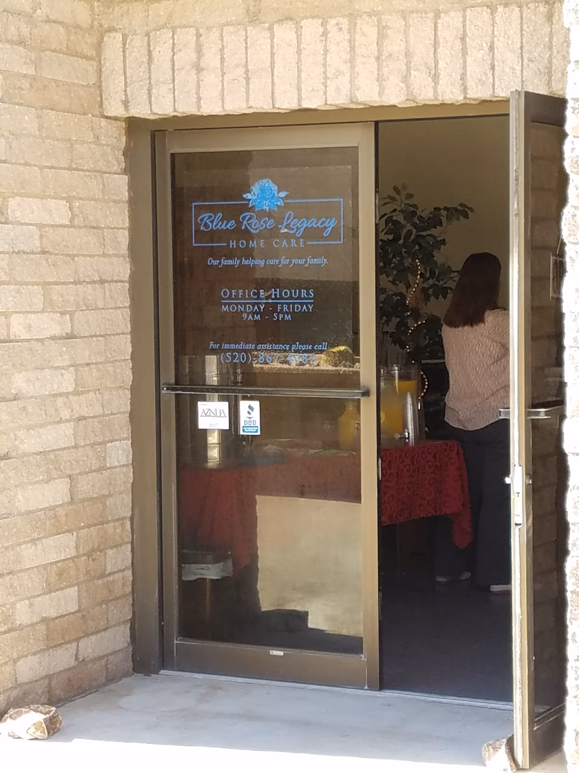 Brick exterior entrance of Blue Rose Legacy Home Care; a person stands inside near the door.