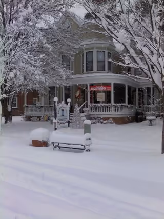 Snow-covered senior care building with a porch and bench at the front.