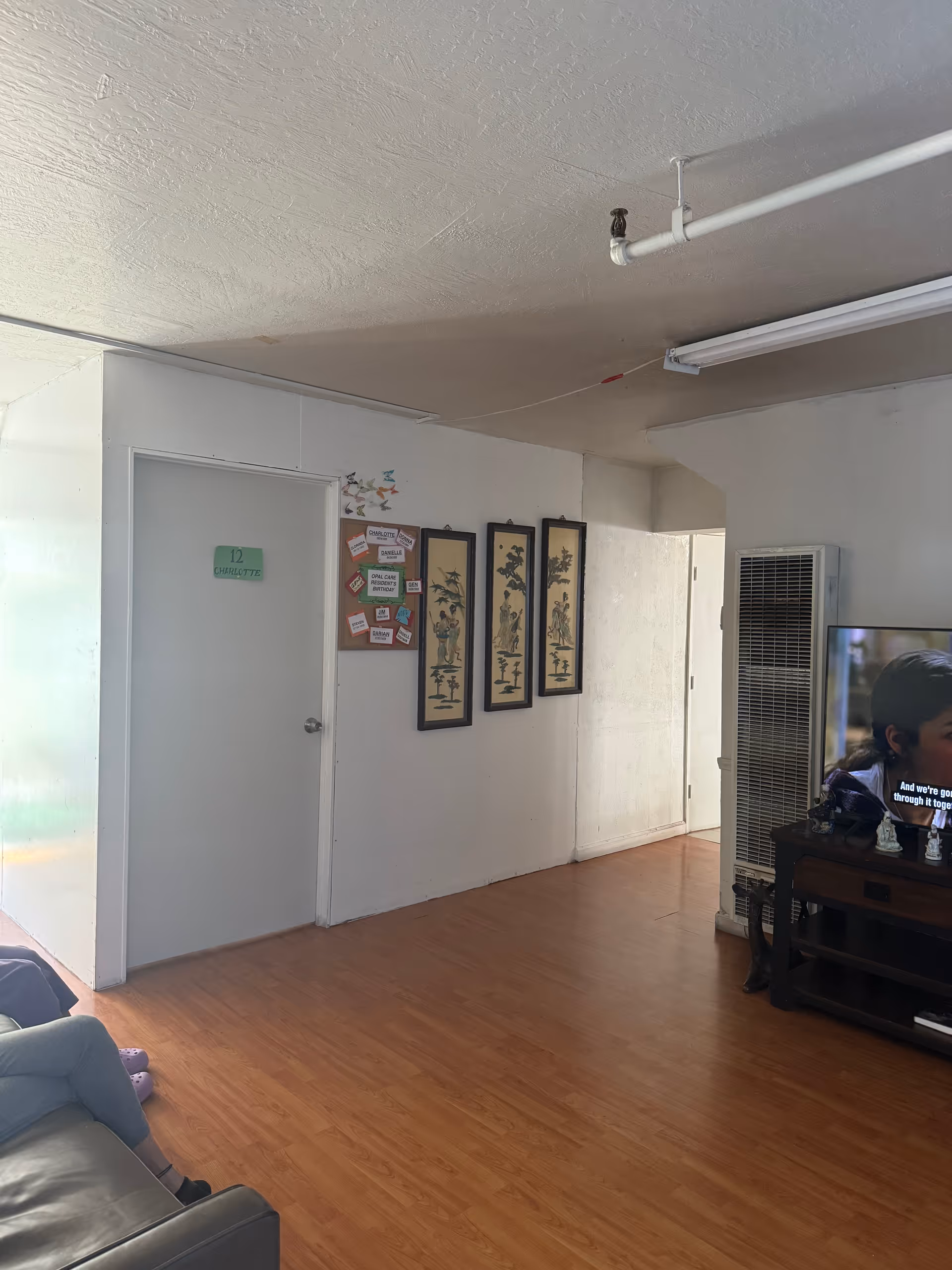 Interior Opal Care lounge with couch, TV, wall art, and doorway.