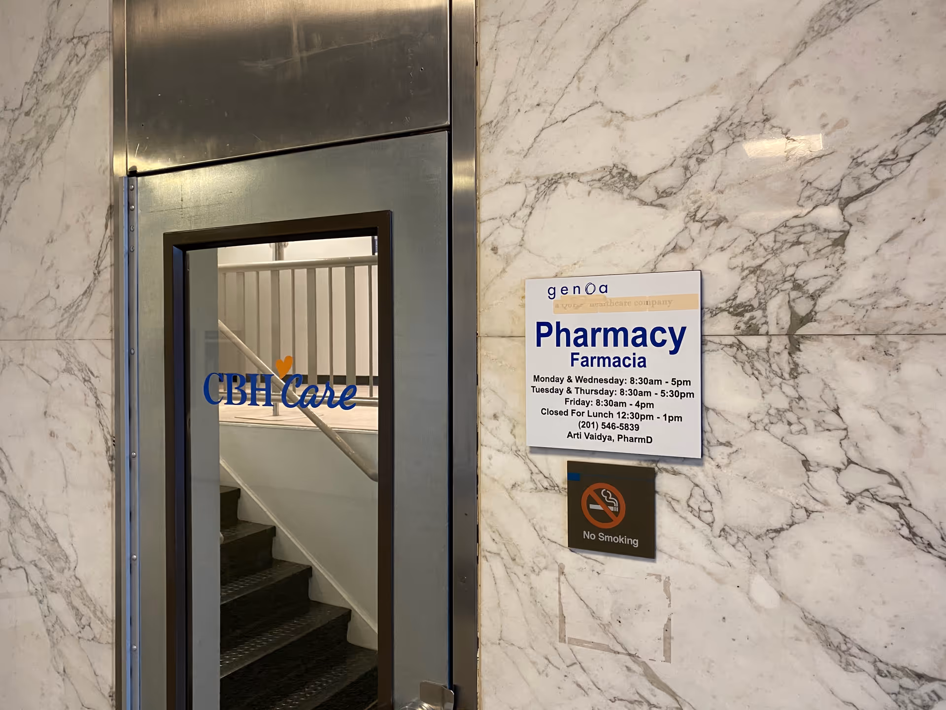 Metal framed glass door with CBH Care logo, marble walls, and a Pharmacy sign.