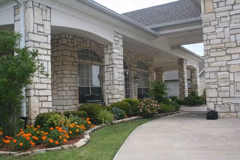 Stone Brook facility exterior with curved walkway, columned entrance, and landscaped garden.
