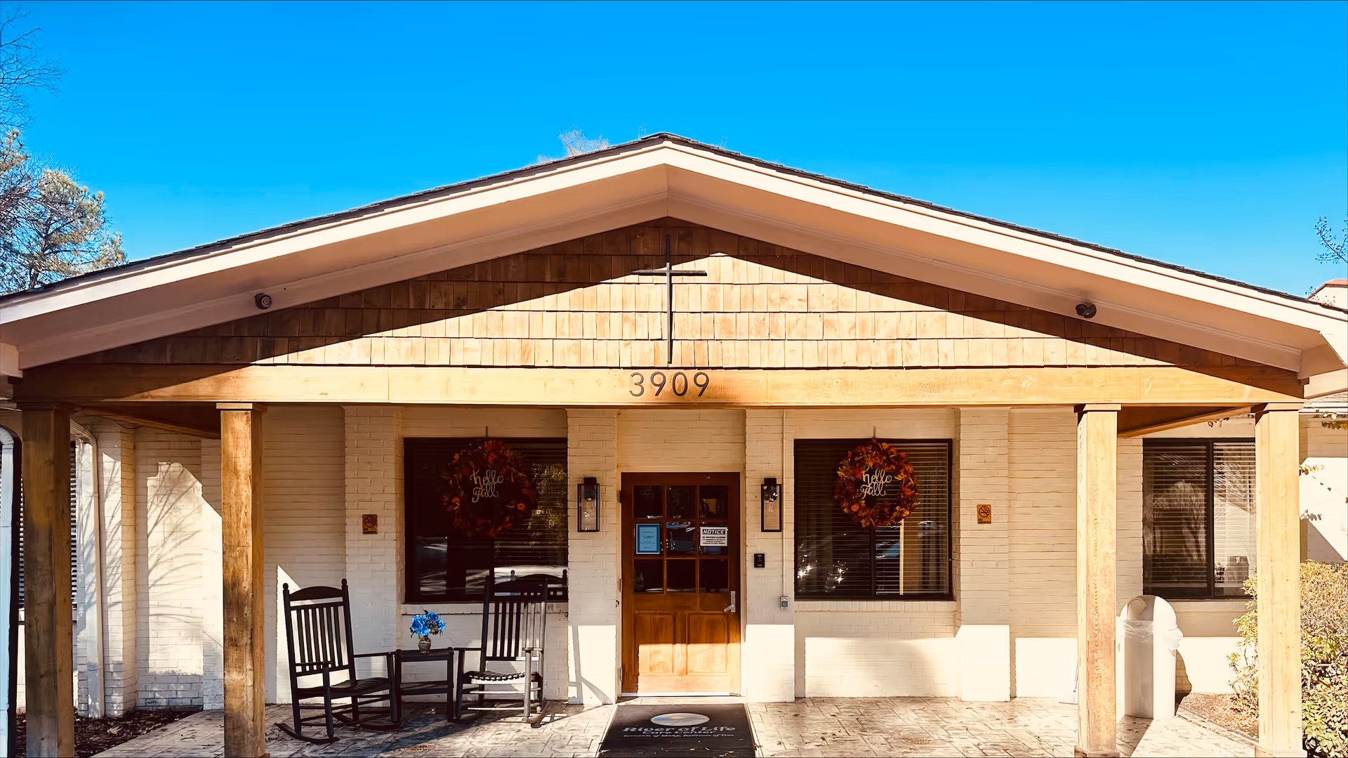A single-story facility entrance with wooden front porch and two rocking chairs.