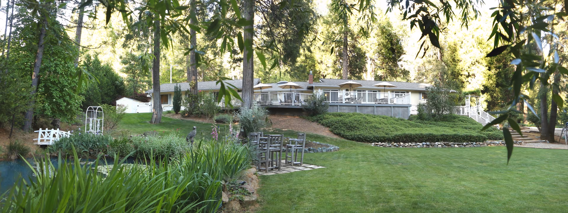 Banner Crest outdoor lawn with pond, greenery, and a decked patio area