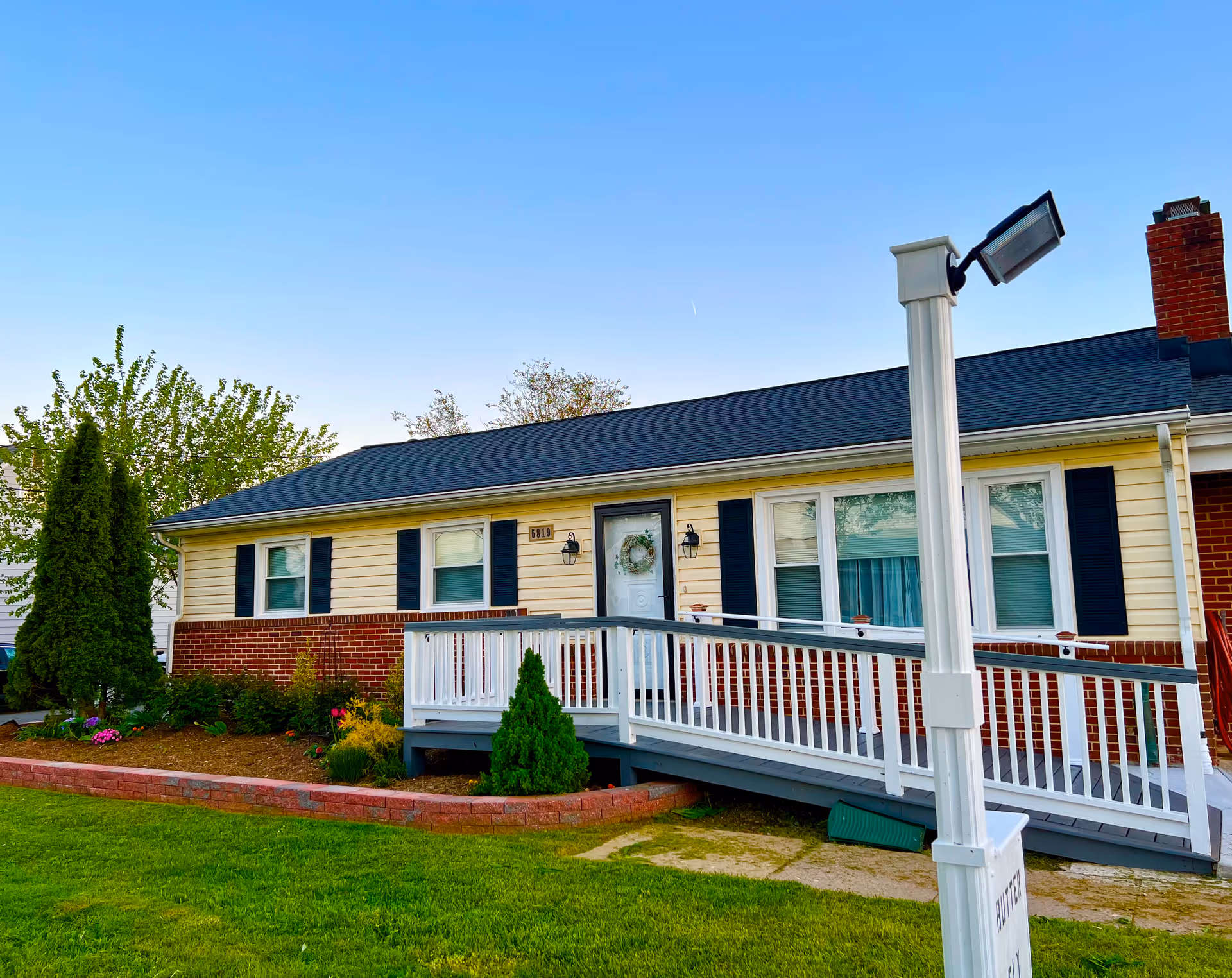 Front exterior of a single-story care residence with a white railing porch and manicured yard
