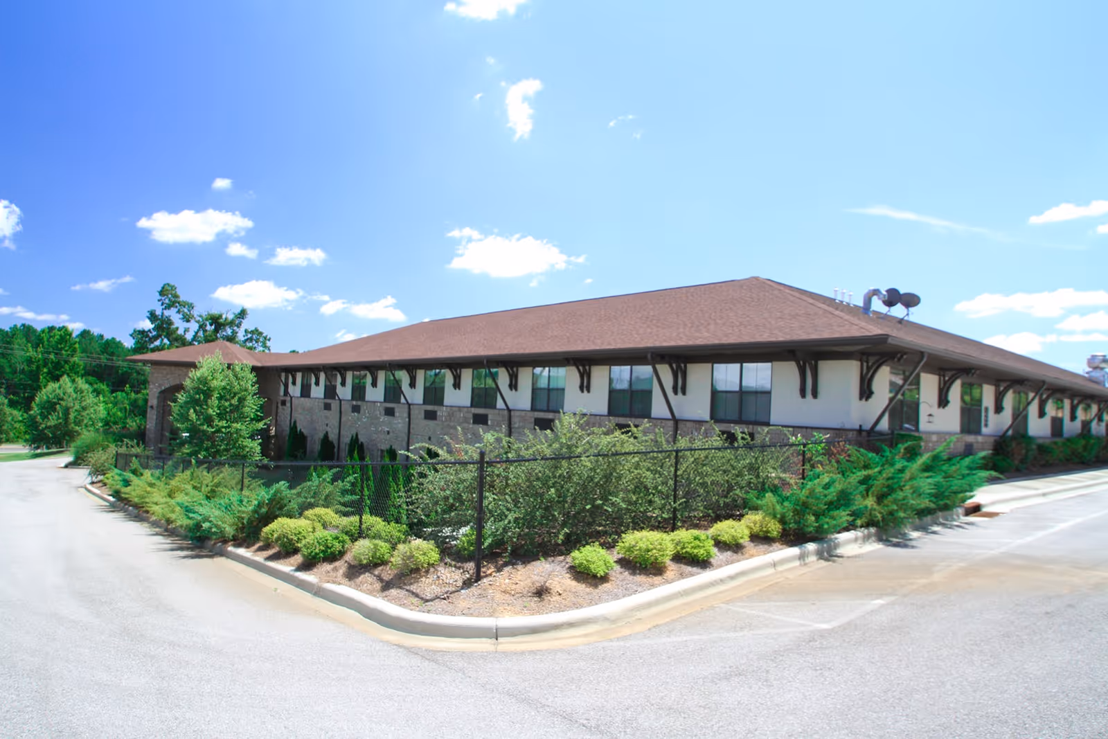 Front exterior of a single-story senior living facility with landscaping and parking.