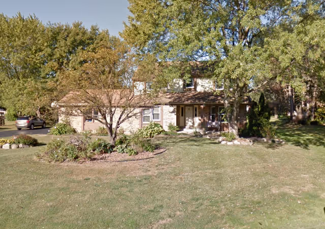 Single-story brick building front at Desert Senior Living Apartments with lawn and trees.