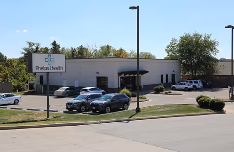 Exterior view of Phelps Health building with parking lot and sign.