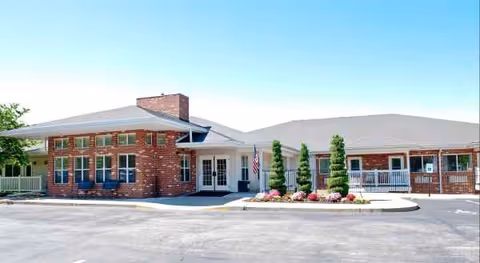Brick senior living facility front with glass entrance and landscaped entry.