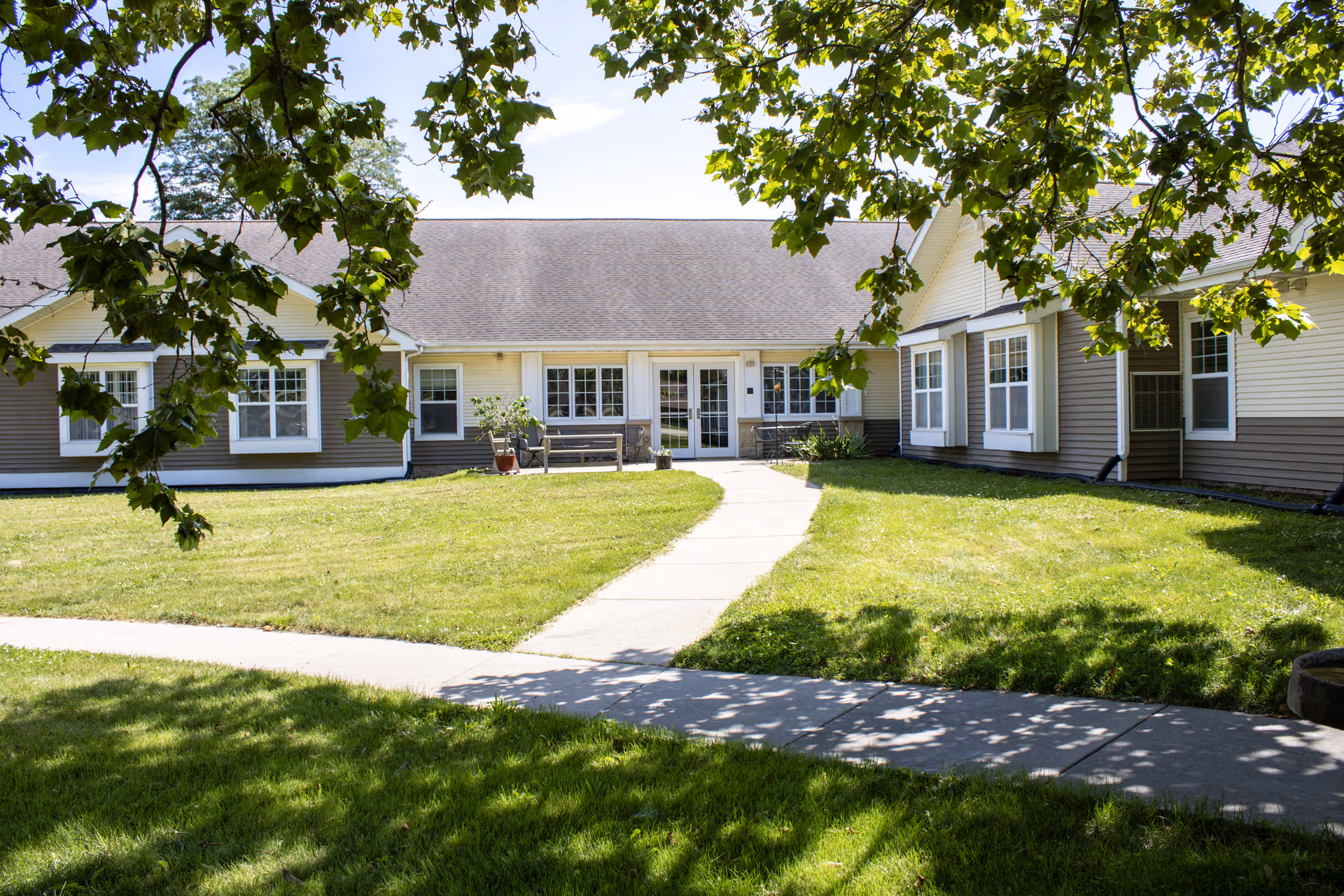 Single-story senior living facility with a curved sidewalk, green lawn, and front entrance.