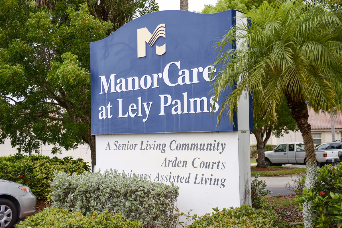 Blue sign reading ManorCare at Lely Palms outside a senior living community.