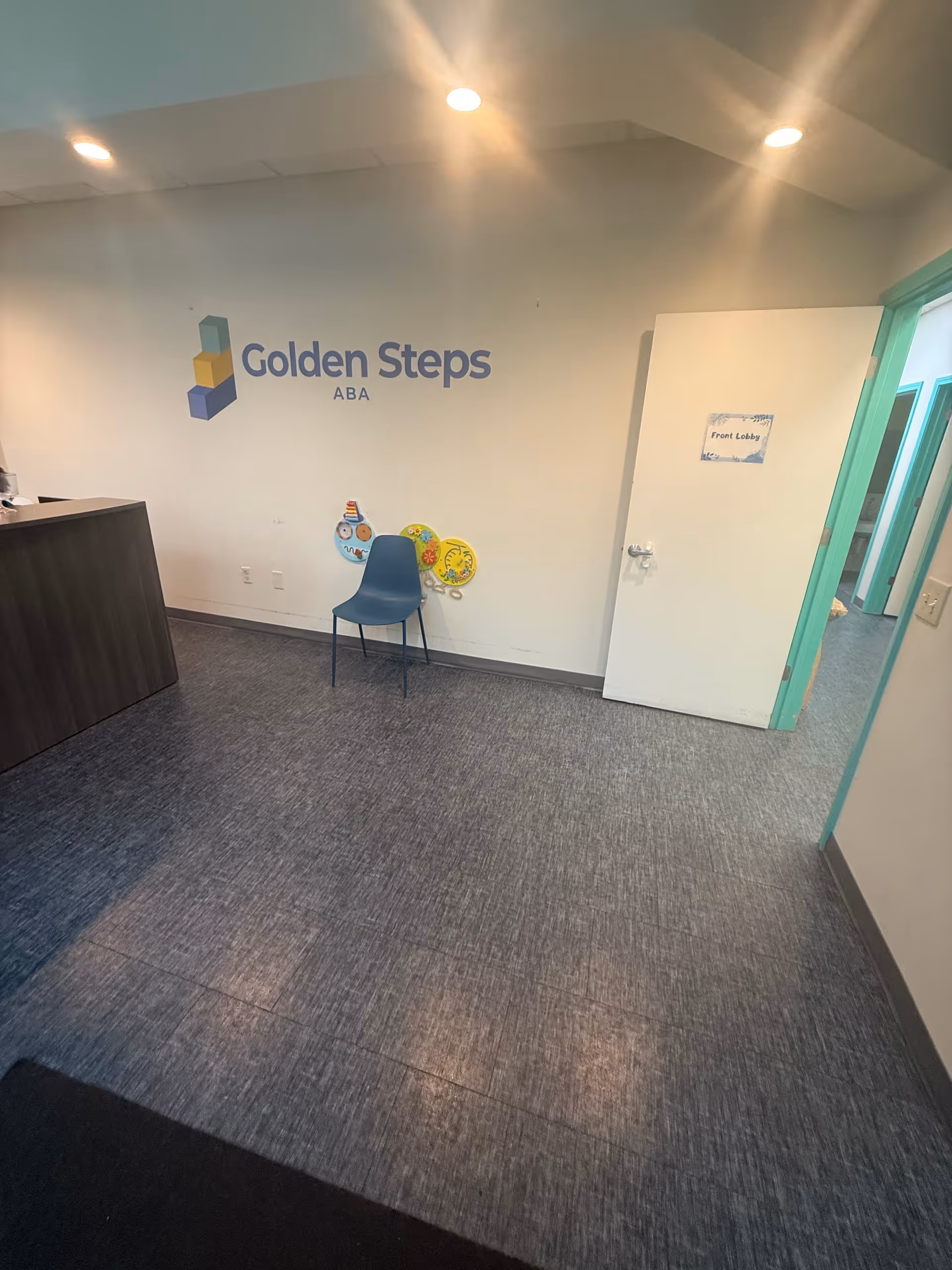 Lobby area with Golden Steps ABA logo on the wall, chair, and doorway.