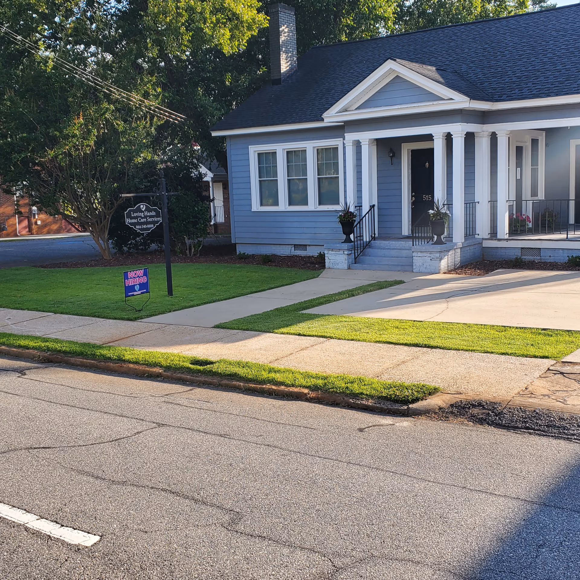 Blue building with a front porch and sign reading Loving Hands Home Care Services.