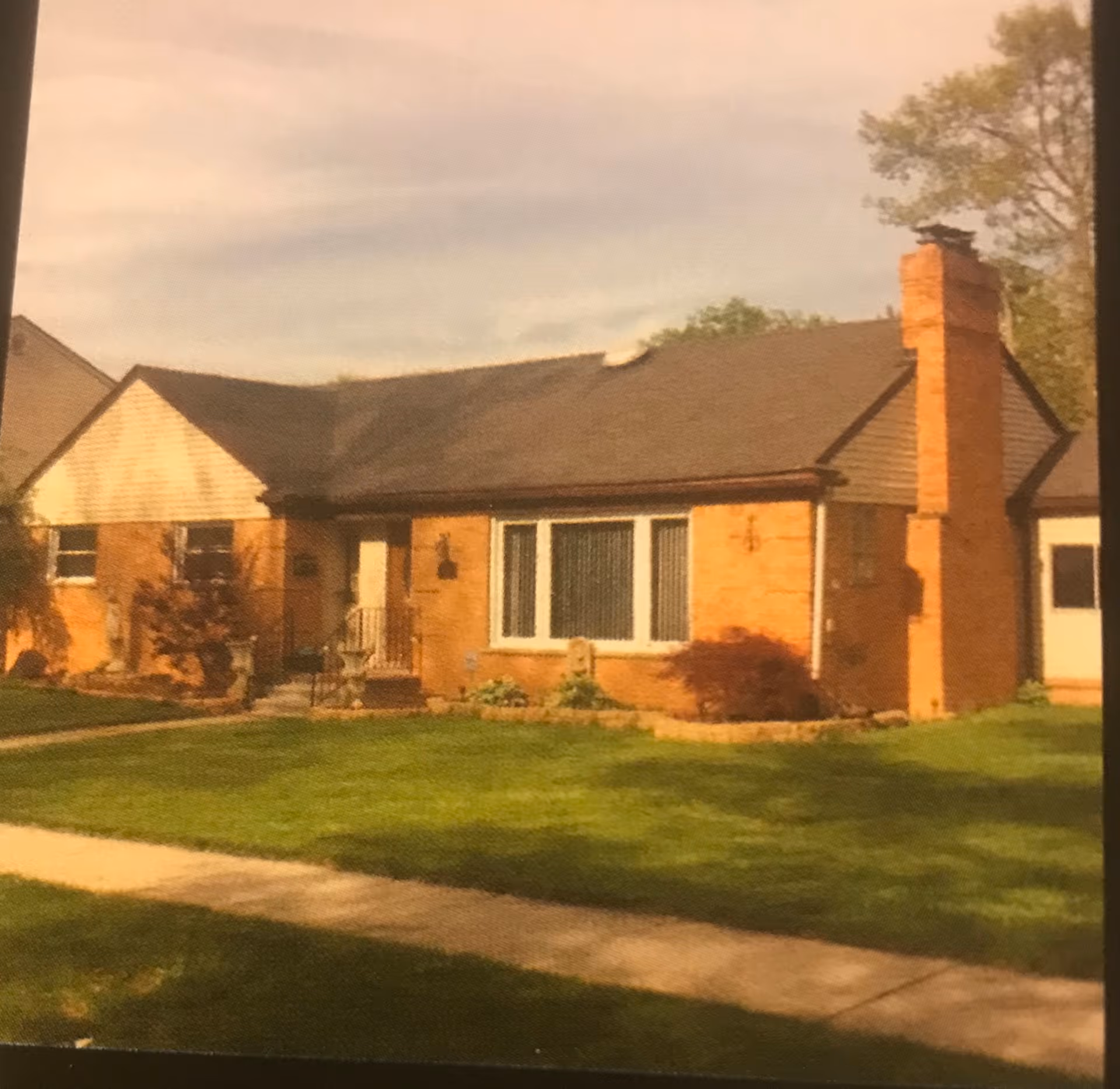 Brick, single-story building with front windows, a chimney, and a well-kept lawn.