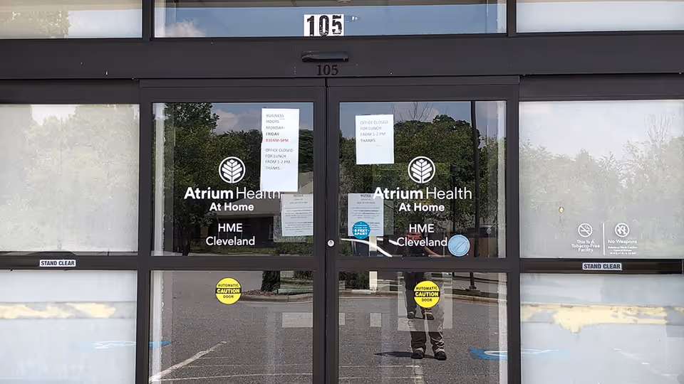 Glass doors with Atrium Health At Home HME Cleveland signage at building entrance.