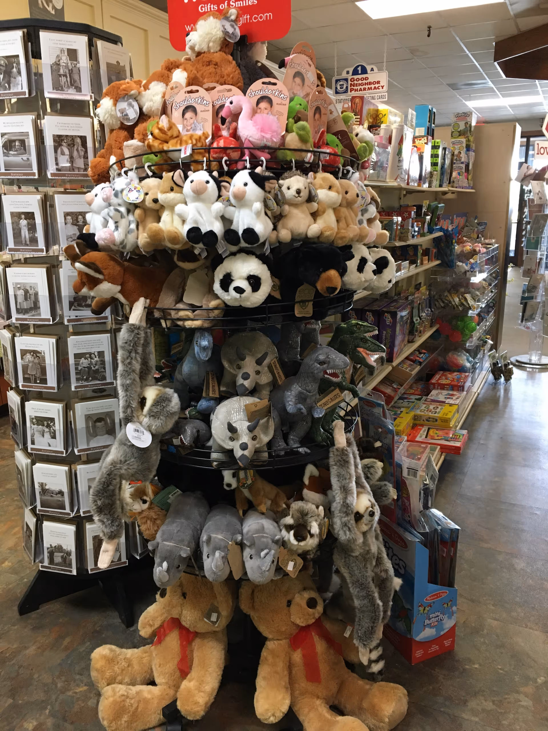 Circular display rack overflowing with plush stuffed animals in a busy retail store.