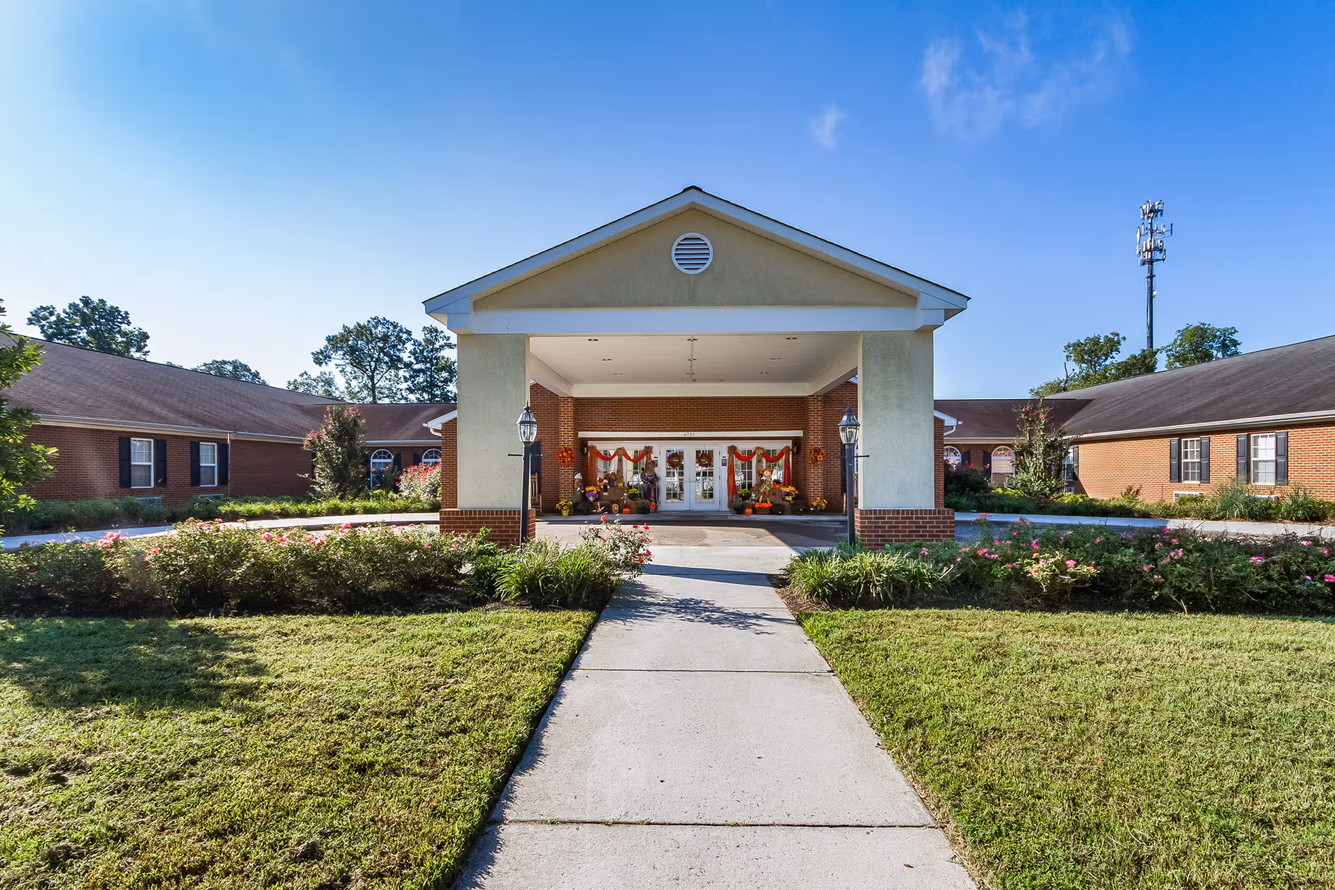 Front entrance of a brick senior living facility with a portico and landscaped walkway.